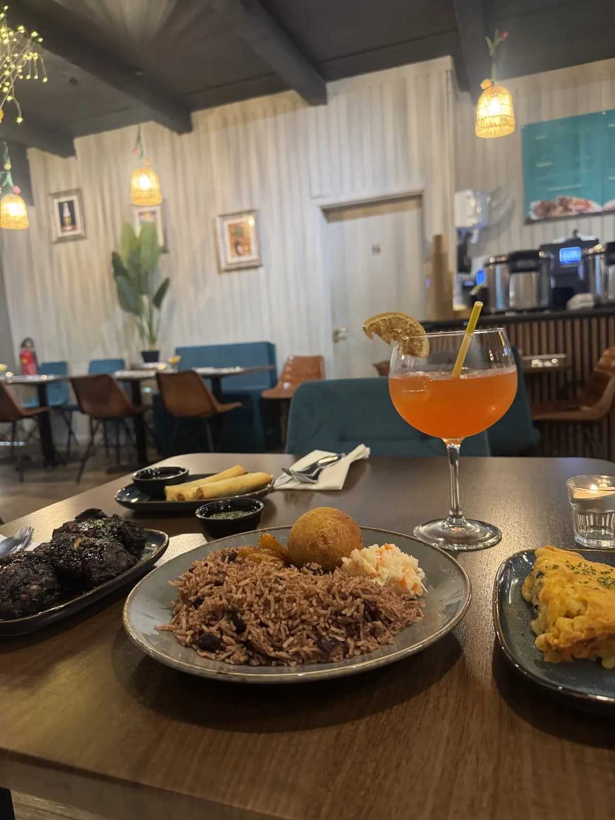 A blue oval platter of glazed jerk chicken, the dining room soft behind it