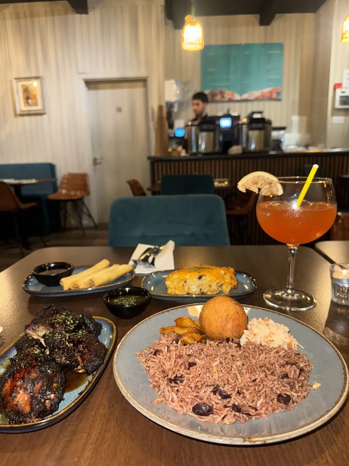 A view down the laid table, cocktail, rice and peas, plantain, with the bar counter behind
